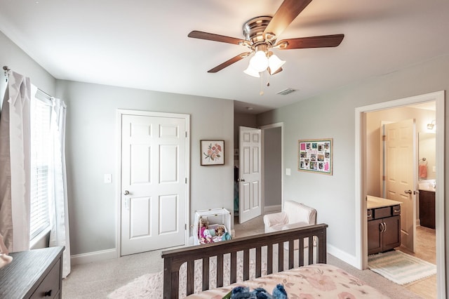 bedroom featuring baseboards, ensuite bath, visible vents, and light colored carpet