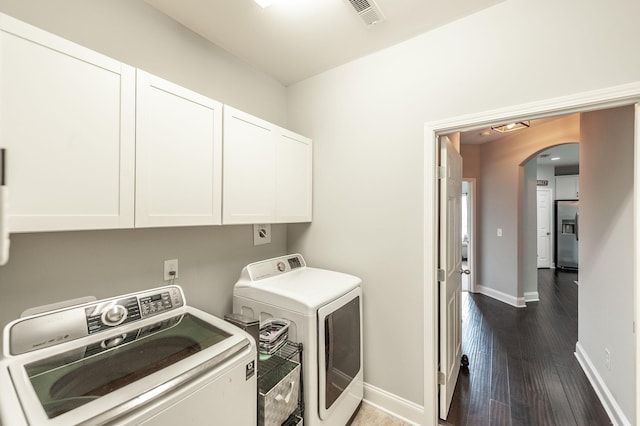 washroom featuring washing machine and dryer, baseboards, visible vents, arched walkways, and cabinet space