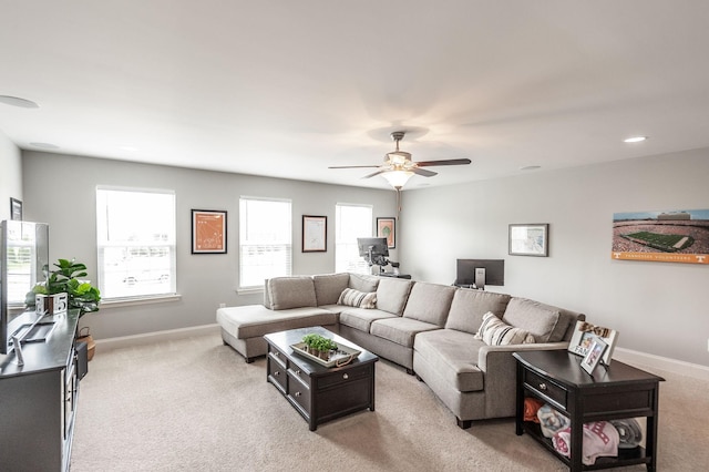 living area featuring light colored carpet, baseboards, and ceiling fan