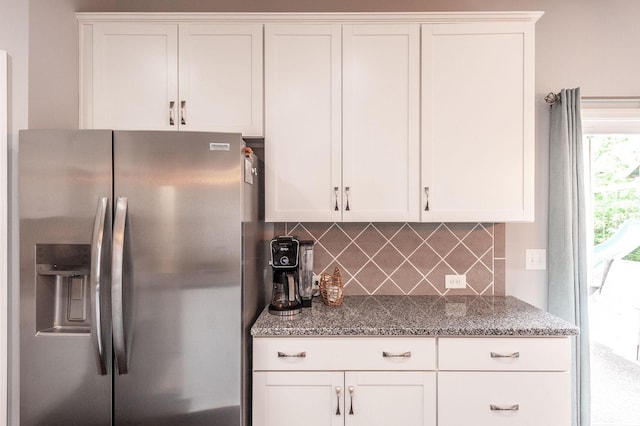 kitchen featuring white cabinetry, tasteful backsplash, stainless steel fridge with ice dispenser, and dark stone counters