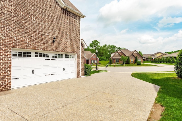 view of side of property featuring an attached garage, a residential view, brick siding, and driveway