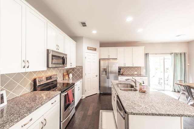 kitchen with a sink, visible vents, white cabinets, light stone countertops, and appliances with stainless steel finishes