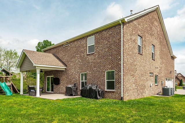 rear view of house with a playground, brick siding, and a lawn