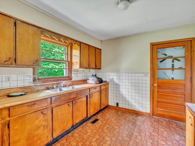 kitchen with light countertops, visible vents, tile walls, and a sink