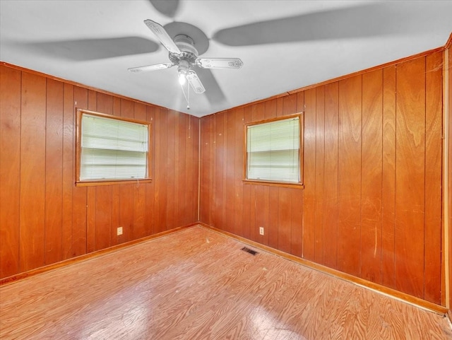 spare room featuring wooden walls, ceiling fan, and wood finished floors