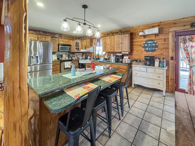 130 Wayne Threatt Rd, Dover, TN 37058 - kitchen with light tile patterned floors, stainless steel appliances, brown cabinetry, a kitchen breakfast bar, and decorative light fixtures