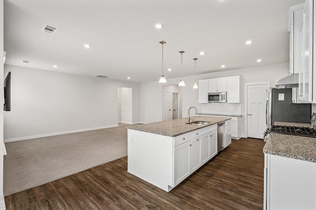 kitchen featuring a sink, stainless steel appliances, tasteful backsplash, a kitchen island with sink, and dark wood-type flooring