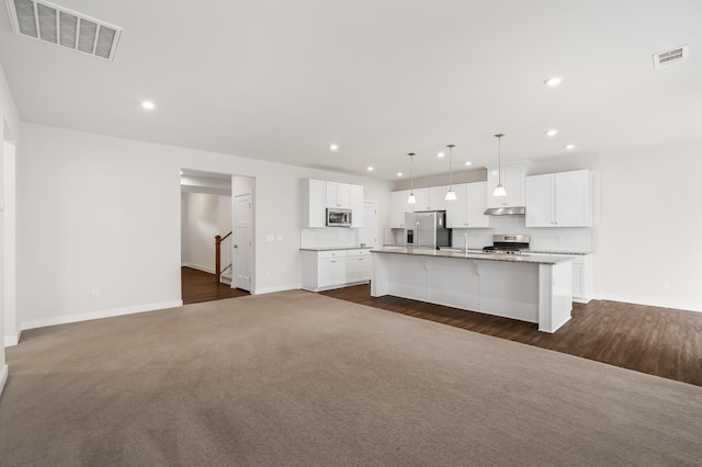 kitchen featuring baseboards, appliances with stainless steel finishes, a kitchen island with sink, and visible vents