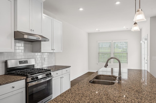 kitchen featuring a sink, dark stone countertops, under cabinet range hood, dark wood-style floors, and stainless steel gas range