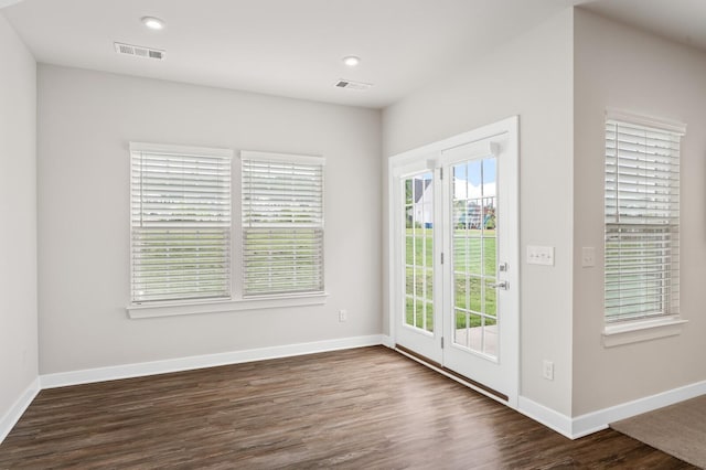empty room with baseboards, dark wood-type flooring, and visible vents
