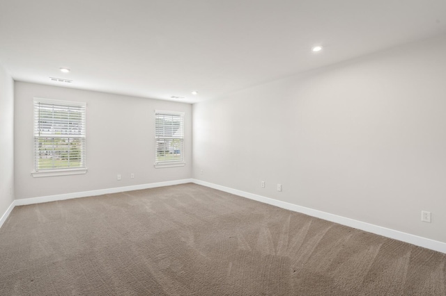 carpeted empty room featuring a wealth of natural light, visible vents, baseboards, and recessed lighting
