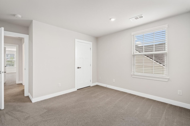empty room with carpet, baseboards, and visible vents