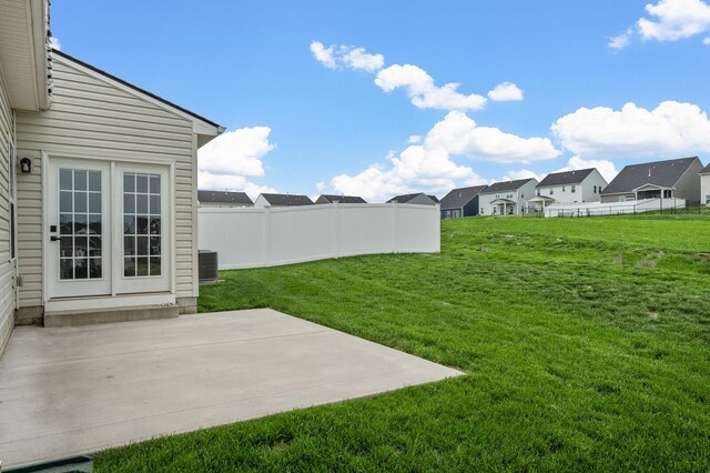 view of yard with a patio, fence, central AC unit, and a residential view