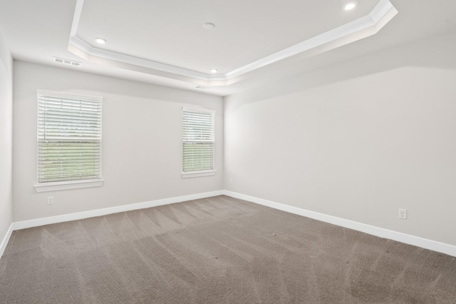empty room featuring carpet, visible vents, recessed lighting, a tray ceiling, and baseboards