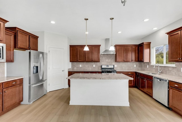 kitchen featuring a sink, wall chimney exhaust hood, stainless steel appliances, light wood-style floors, and tasteful backsplash