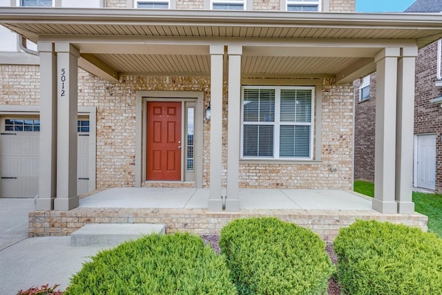 view of exterior entry with a porch and brick siding