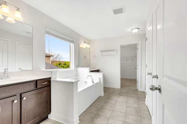 full bath featuring vanity, visible vents, tile patterned floors, a spacious closet, and a garden tub