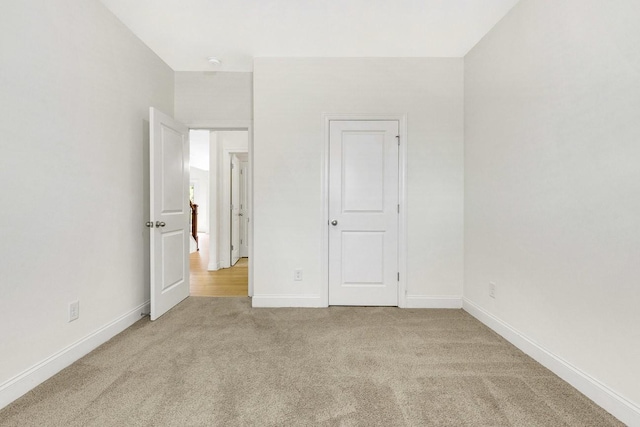 unfurnished bedroom with baseboards and light colored carpet