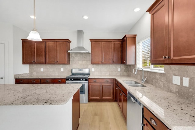 kitchen with a sink, wall chimney exhaust hood, stainless steel appliances, light wood-type flooring, and light stone counters
