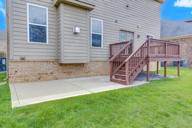 back of house with a lawn, a patio, brick siding, and a wooden deck