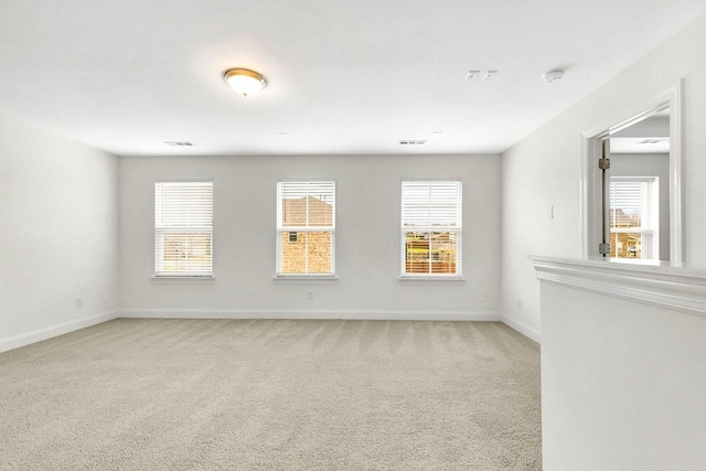 unfurnished room featuring plenty of natural light, light carpet, and baseboards