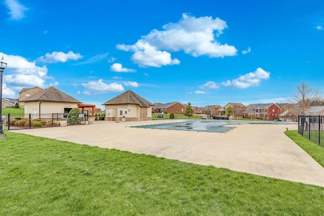 community pool with a yard, fence, a patio area, and a residential view