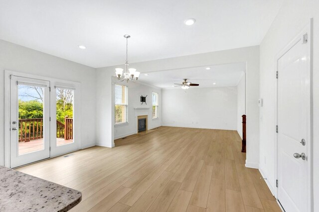 unfurnished living room featuring light wood-style floors, baseboards, ceiling fan with notable chandelier, and recessed lighting