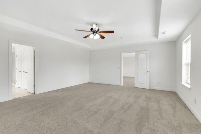 interior space featuring light colored carpet, a raised ceiling, and ceiling fan