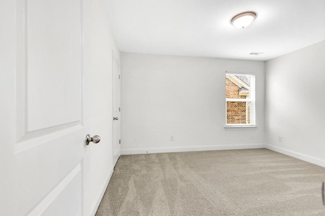 spare room with light colored carpet and baseboards