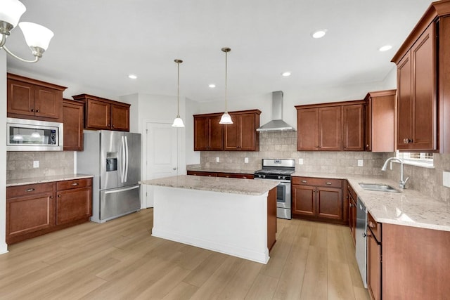 kitchen with a sink, wall chimney exhaust hood, light wood-style flooring, backsplash, and appliances with stainless steel finishes