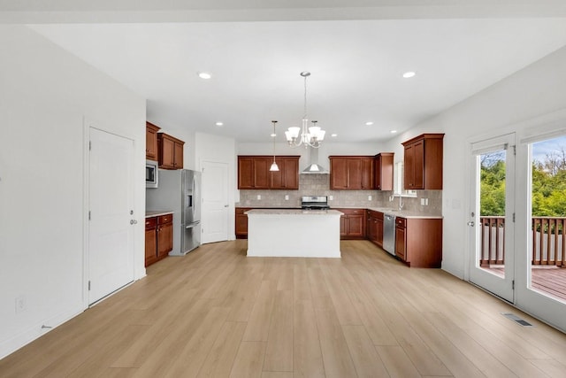 kitchen with a sink, a chandelier, backsplash, light countertops, and appliances with stainless steel finishes