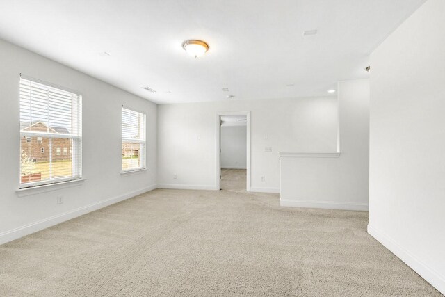 unfurnished room with light carpet and baseboards