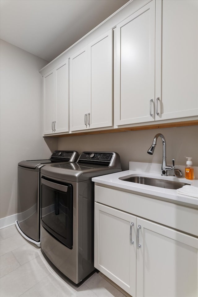 washroom featuring washing machine and dryer, a sink, cabinet space, baseboards, and light tile patterned flooring