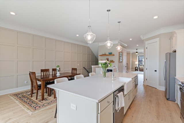 kitchen with a sink, stainless steel appliances, a kitchen island with sink, ceiling fan, and light wood-style floors