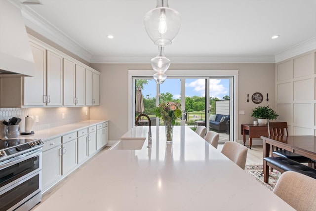 interior space with pendant lighting, crown molding, white cabinets, double oven range, and custom range hood