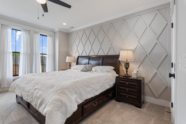 bedroom with crown molding, visible vents, a decorative wall, baseboards, and light colored carpet