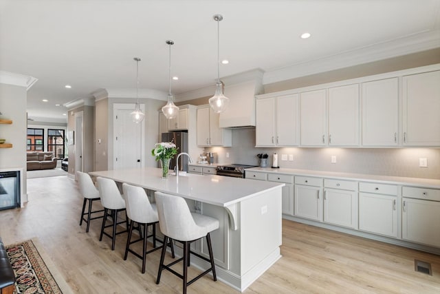 kitchen featuring an island with sink, crown molding, a kitchen bar, and appliances with stainless steel finishes