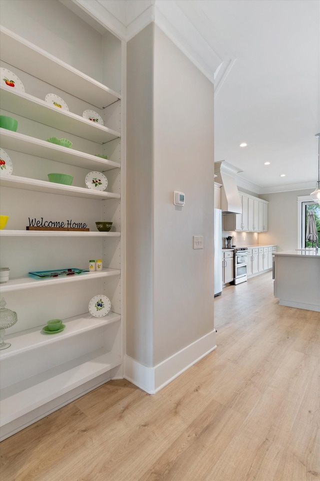 hallway with light wood-type flooring, baseboards, ornamental molding, and recessed lighting