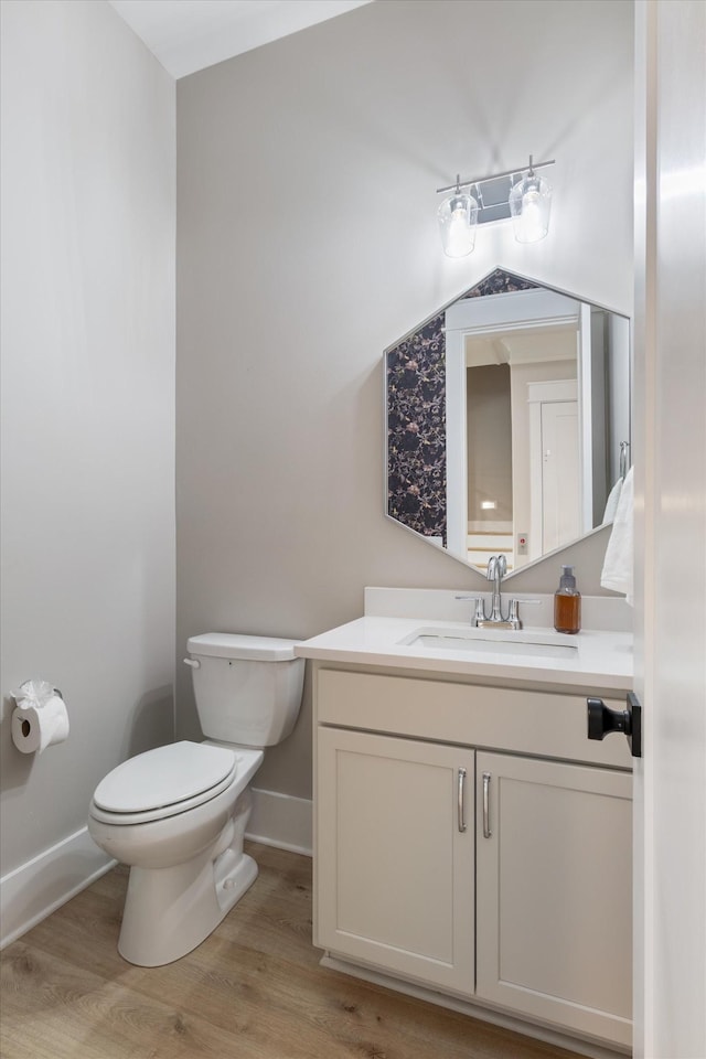 bathroom featuring toilet, baseboards, vanity, and wood finished floors