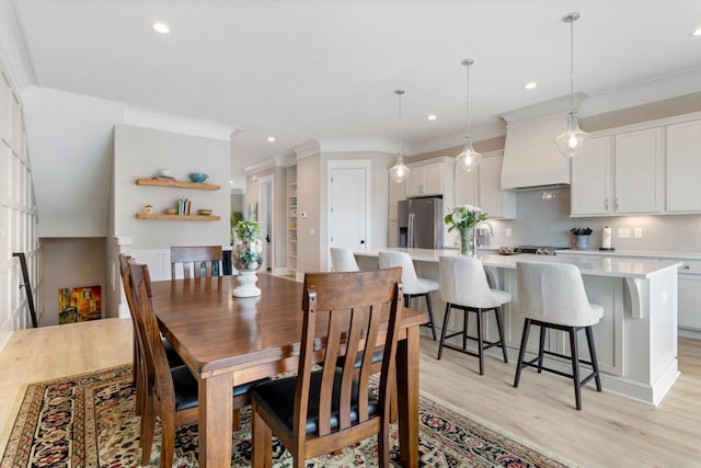 dining area featuring ornamental molding, light wood-type flooring, and recessed lighting