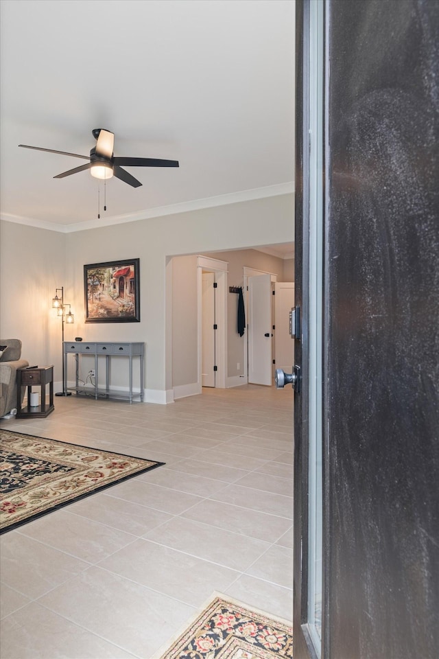 foyer entrance featuring ceiling fan, crown molding, baseboards, and light tile patterned floors