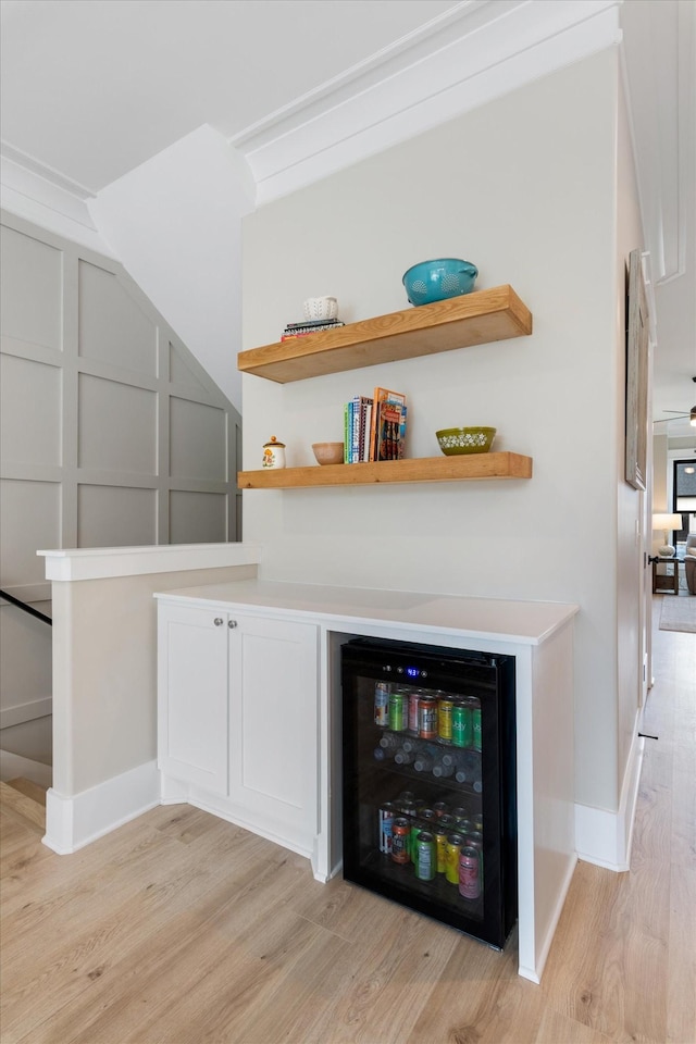 bar featuring wine cooler, baseboards, and light wood finished floors