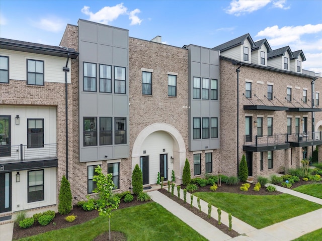 townhome / multi-family property with brick siding and a front lawn