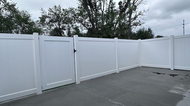view of gate with fence and a patio area