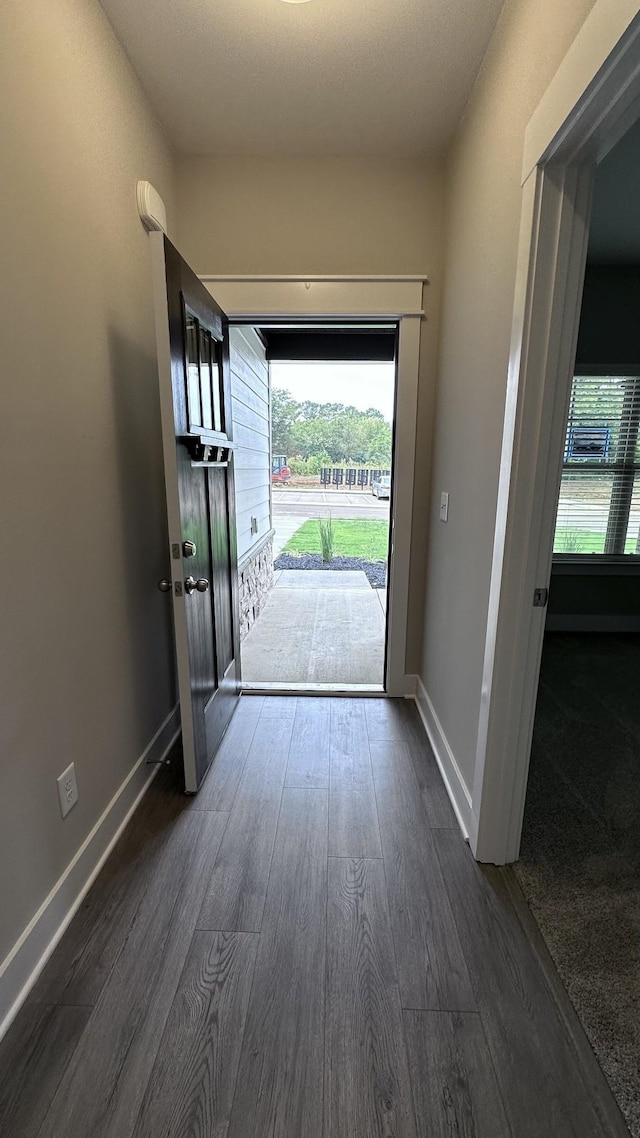 doorway to outside featuring dark wood finished floors, a wealth of natural light, and baseboards