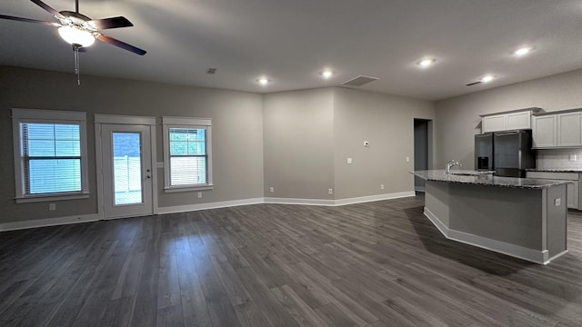 kitchen featuring a sink, black fridge with ice dispenser, visible vents, dark wood finished floors, and open floor plan