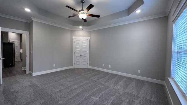 unfurnished bedroom with a raised ceiling, baseboards, and dark carpet