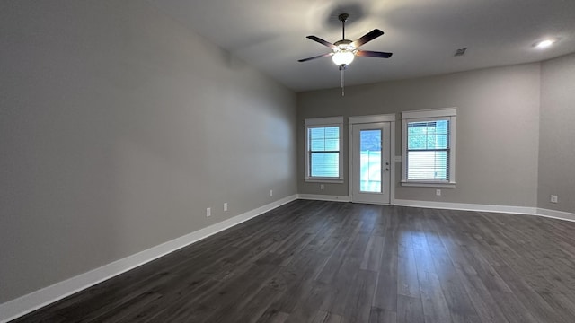 empty room featuring visible vents, baseboards, ceiling fan, and dark wood-style floors