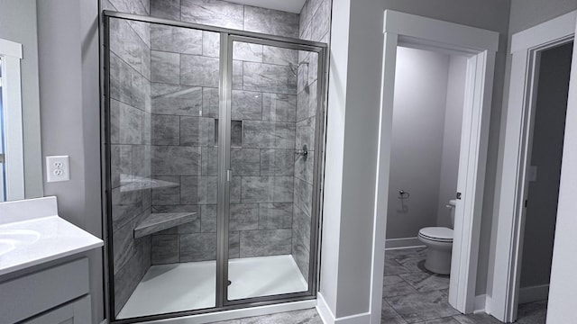full bathroom with toilet, marble finish floor, vanity, a stall shower, and baseboards