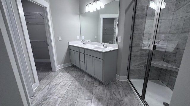 full bath with double vanity, baseboards, a shower stall, and a sink